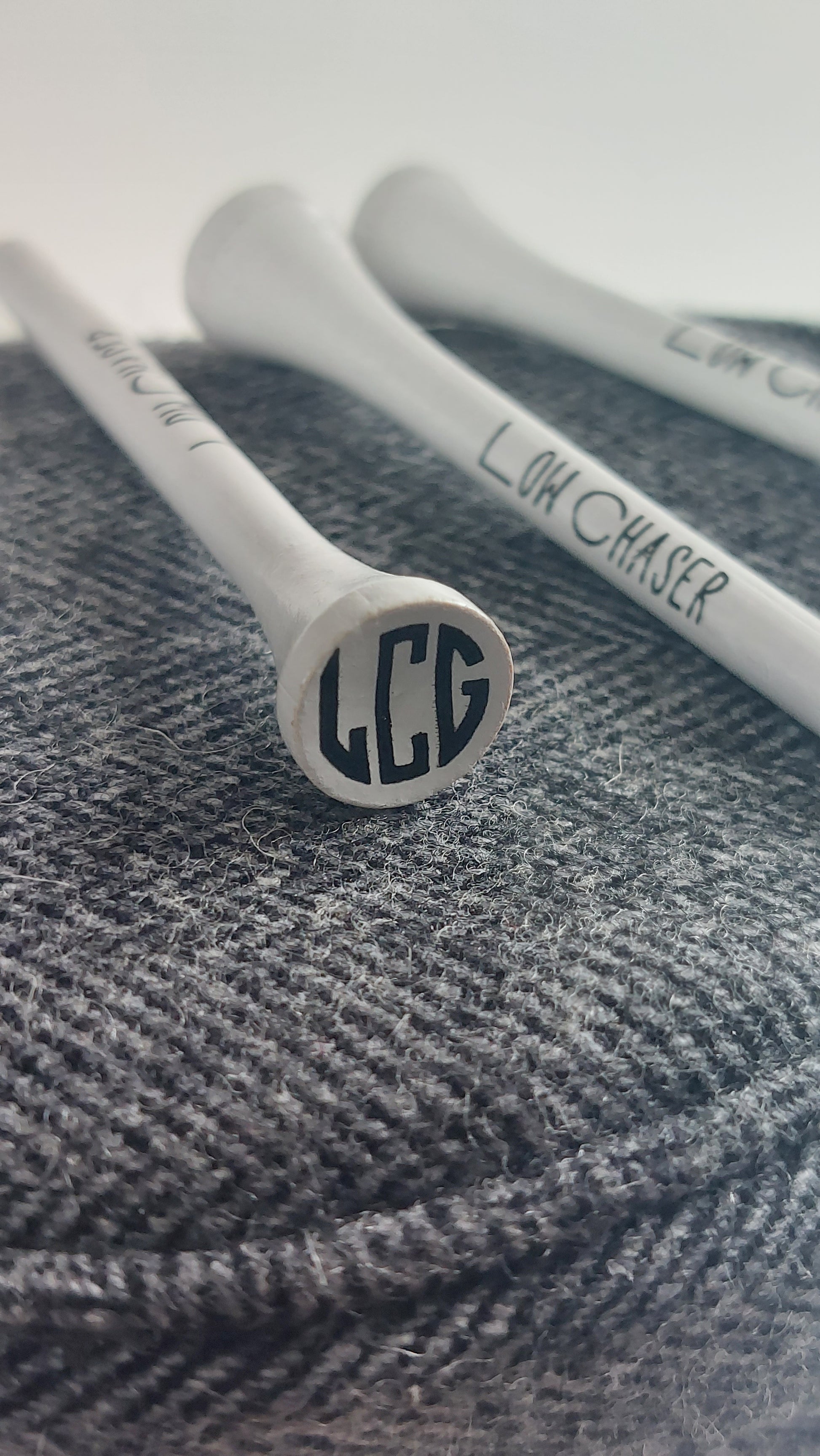 Low Chaser Golf white tees, on a charcoal headcover.