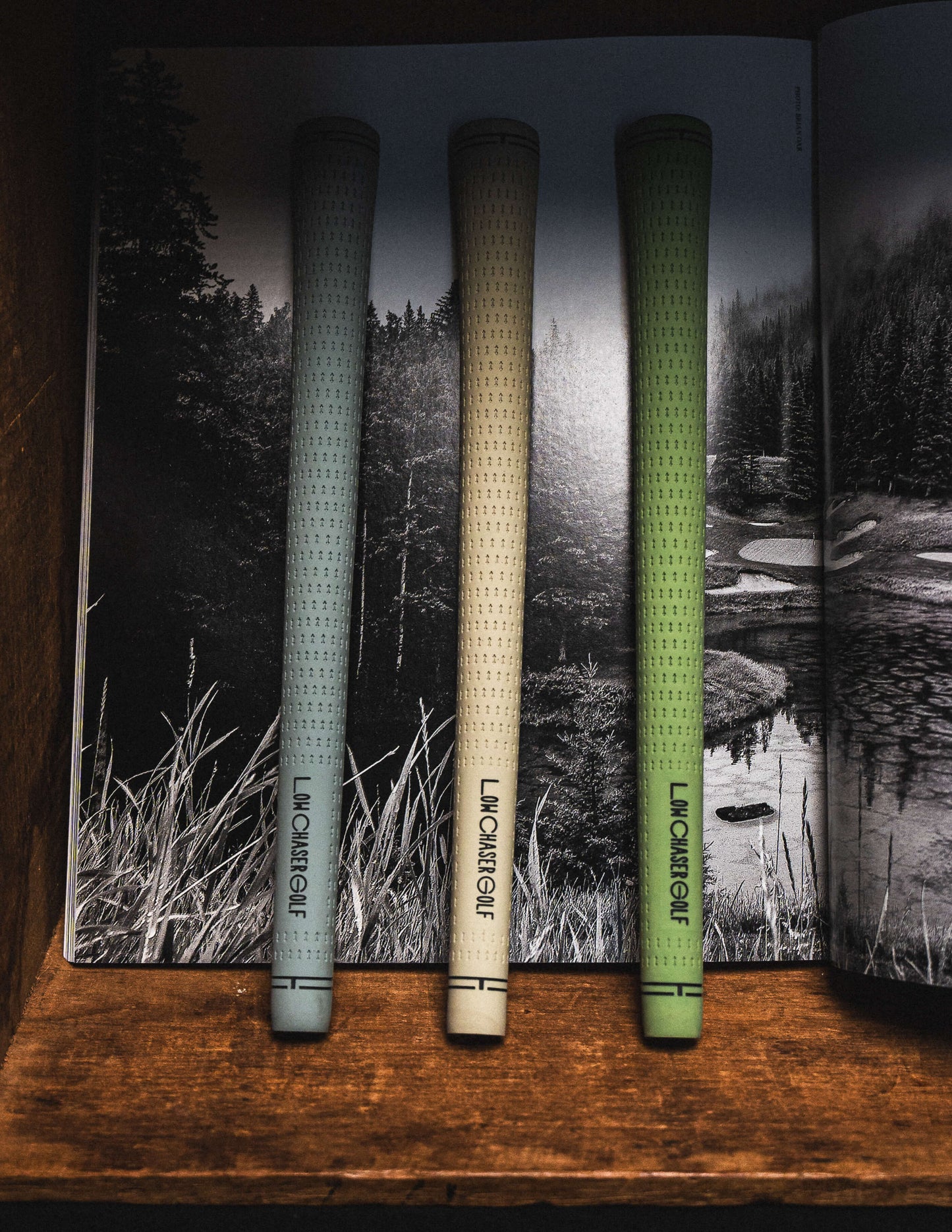 Baby blue, cream, and pastel green golf grips by Low Chaser Golf, on a black and white magazine cove