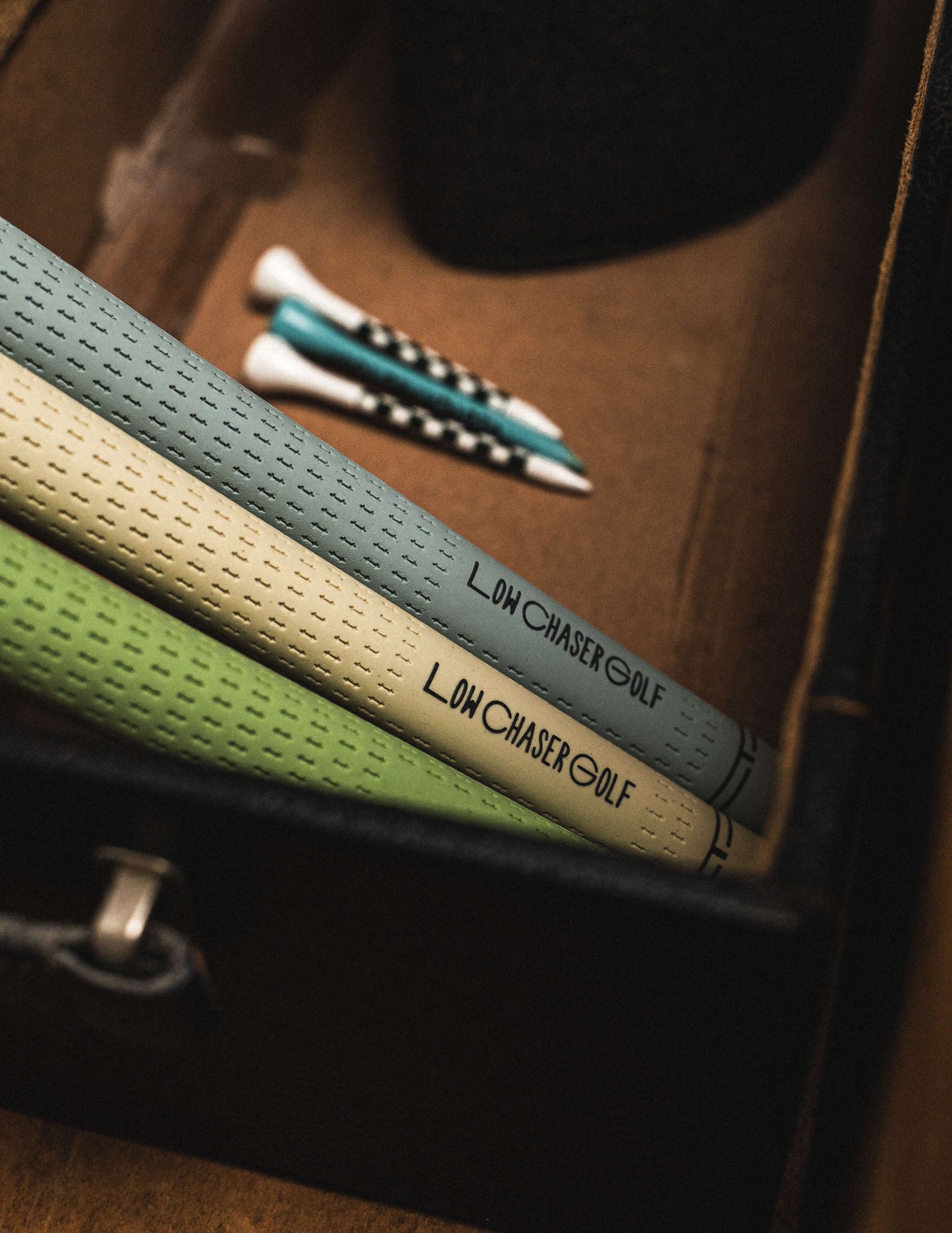 Baby Blue, cream and pastel green Golf Grips by Low Chaser Golf, set in a dark suitcase