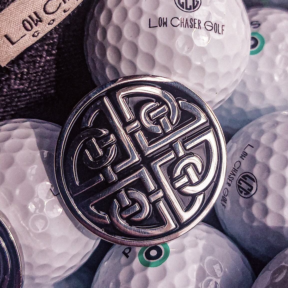 Golf Ball Marker With Celtic Shield Knot Design Sitting on Golf Balls