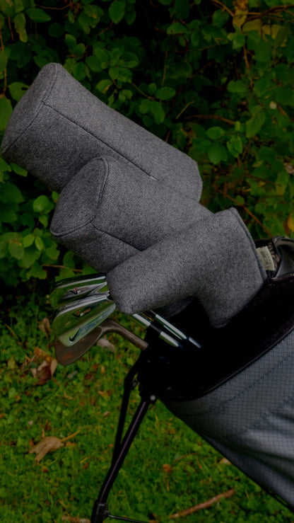 A set of golf clubs, in a stand golf bag. The set has charcoal barrel headcovers on the driver and fairway wood, and a charcoal  cover on the blade putter.