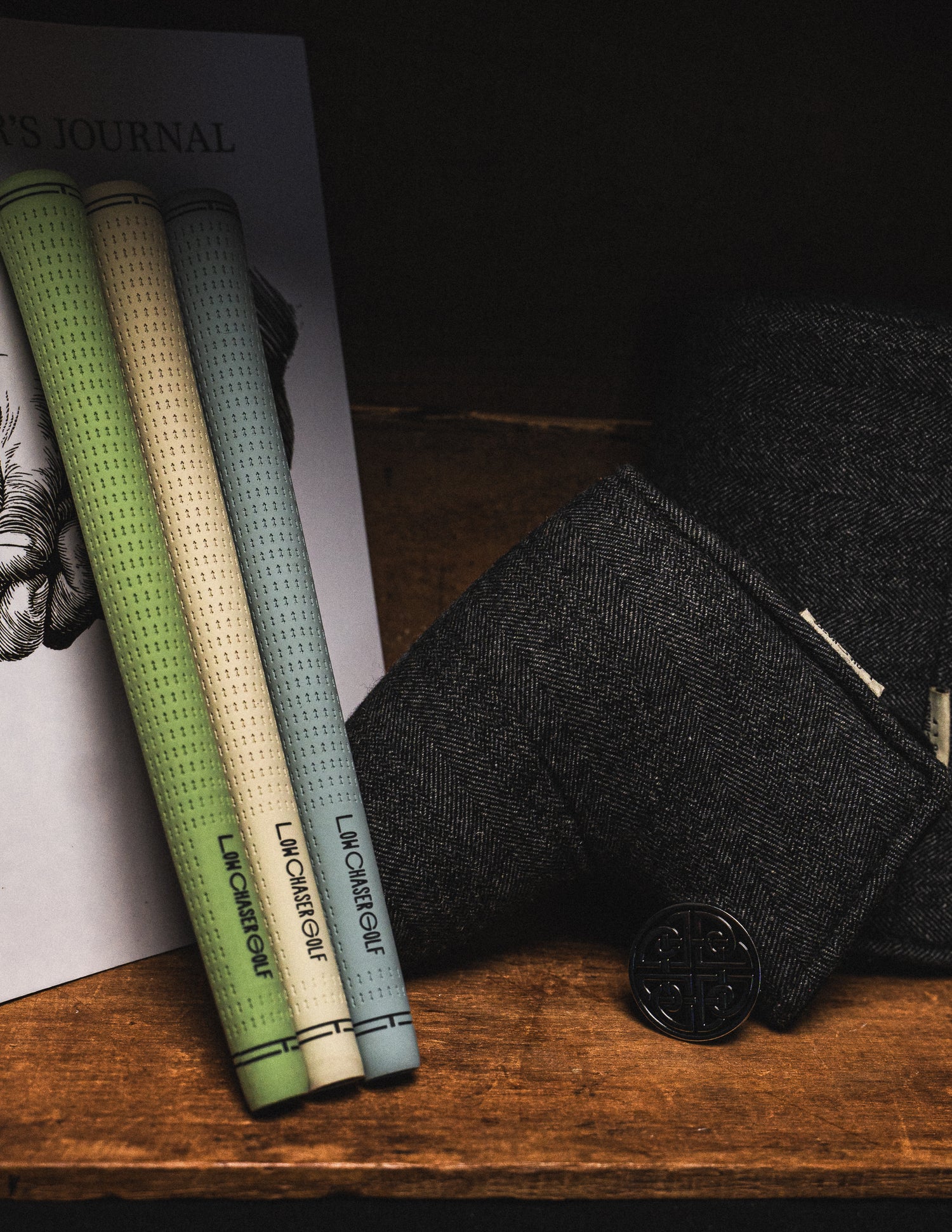 Cream, green and blue grips against a copy of the golfers journal, and charcoal headcovers.